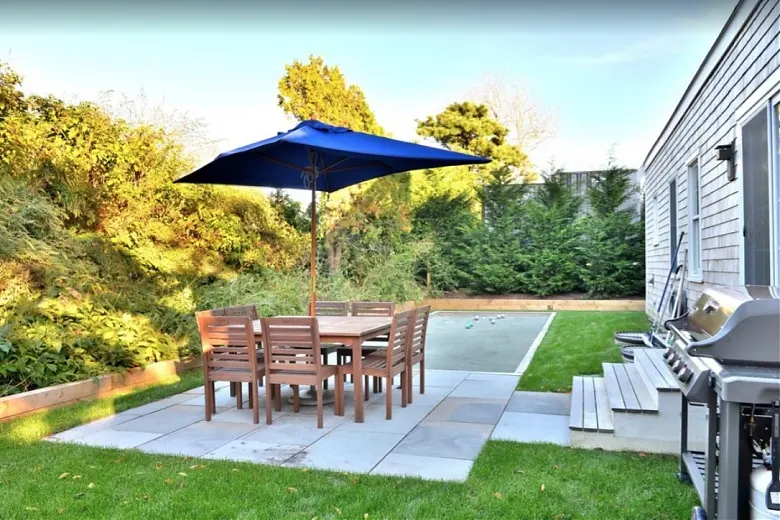 Patio with dining set beside a shingled Nantucket home